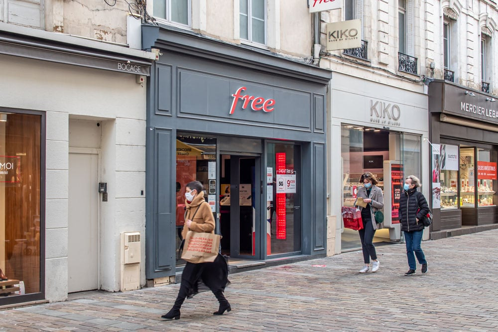 people walking on a street with a store front